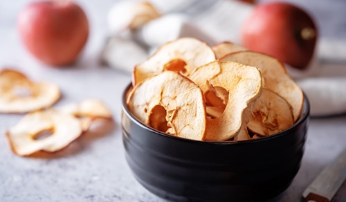 fuji apples sliced dried fruit in a bowl and fresh fruit in the background