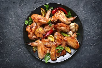 Tequila Lime Chicken Wings on a plate on a black table.