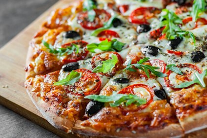 A fresh-made pizza with cheese, herbs and vegetables.