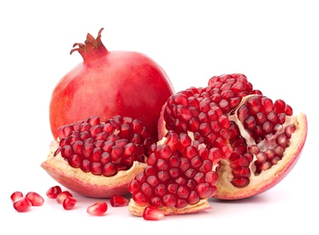 fresh cut open pomegranate in front of a whole