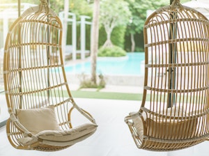 Two egg chairs hanging near a pool.