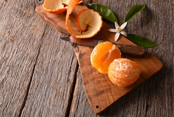 A Minneola Tangelo peeled on a woodend cutting board.