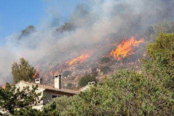 wild fire burning on hill near homes