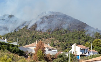 wild fire burning on hill near homes