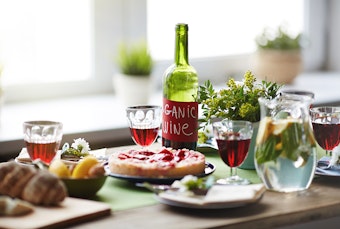 A dining table with food and homemade wine, and a pitcher of water.