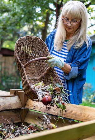 composting woman dumping scraps into bin