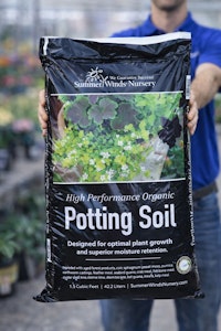 summerwinds associate holding a bag of summerwinds high performance organic potting soil out in front of him