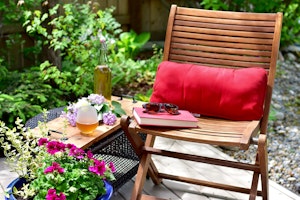 Small space garden with small patio furniture and potted petunias and other plants around.