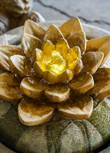 A closeup of a stone bubbler fountain with a flower petal shapped top.