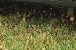 A closeup of a core aerator machine being used to aerate a lawn.