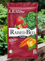A bag of E.B. Stone Organics Raised Bed Potting or Planting with a raised garden vegetable bed in the background.