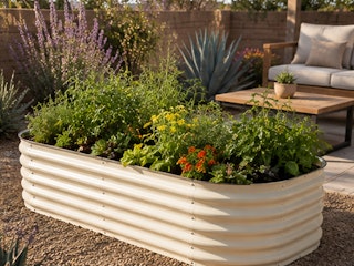 A cream raised garden bed filled with a variety of vegetables, herbs and flowers near a seating area in a Southwest backyard.