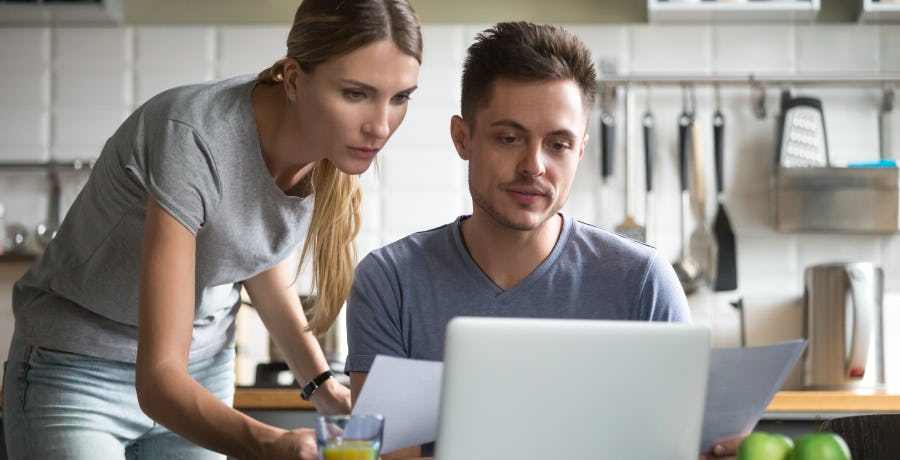 Man and woman looking at a laptop and documents