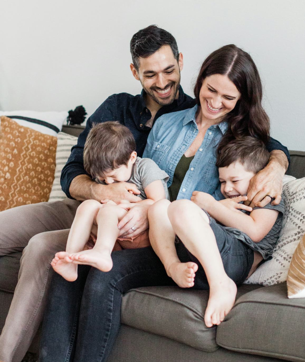 A couple and their two kids hanging out on a couch