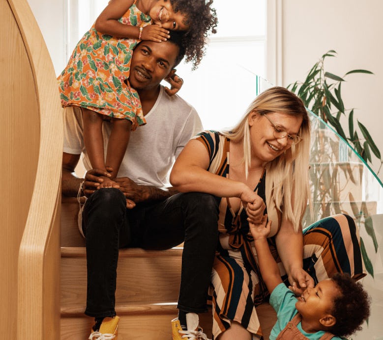 A couple and their two kids hanging out on a set of stairs
