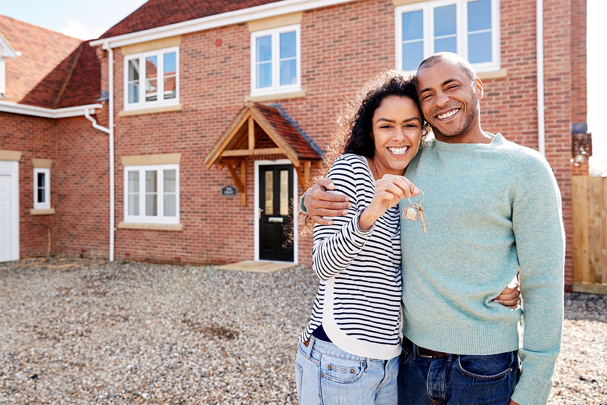 Couple standing in front of a home holding keys