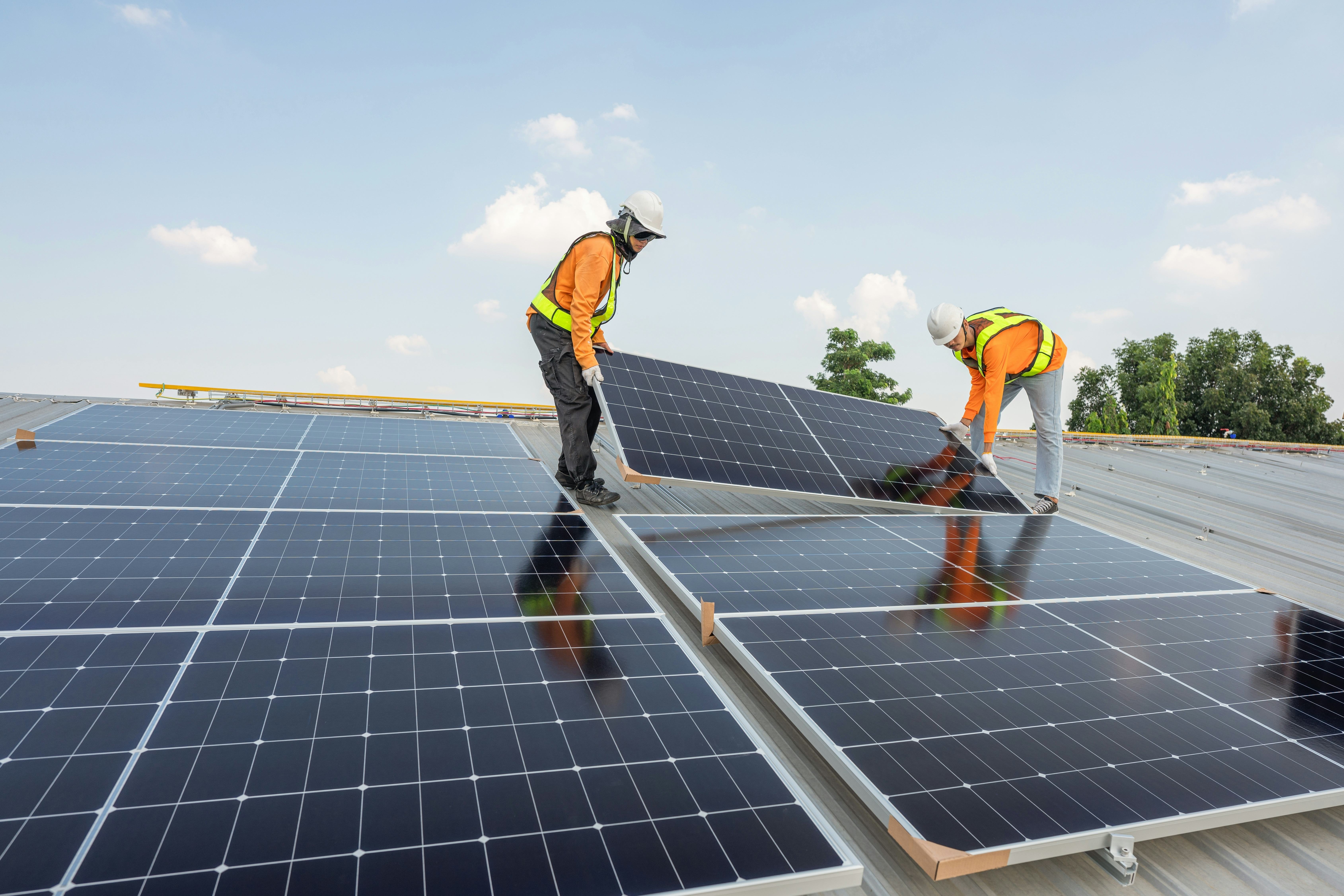 Men on a roof installing solar panels Construction workers installing solar