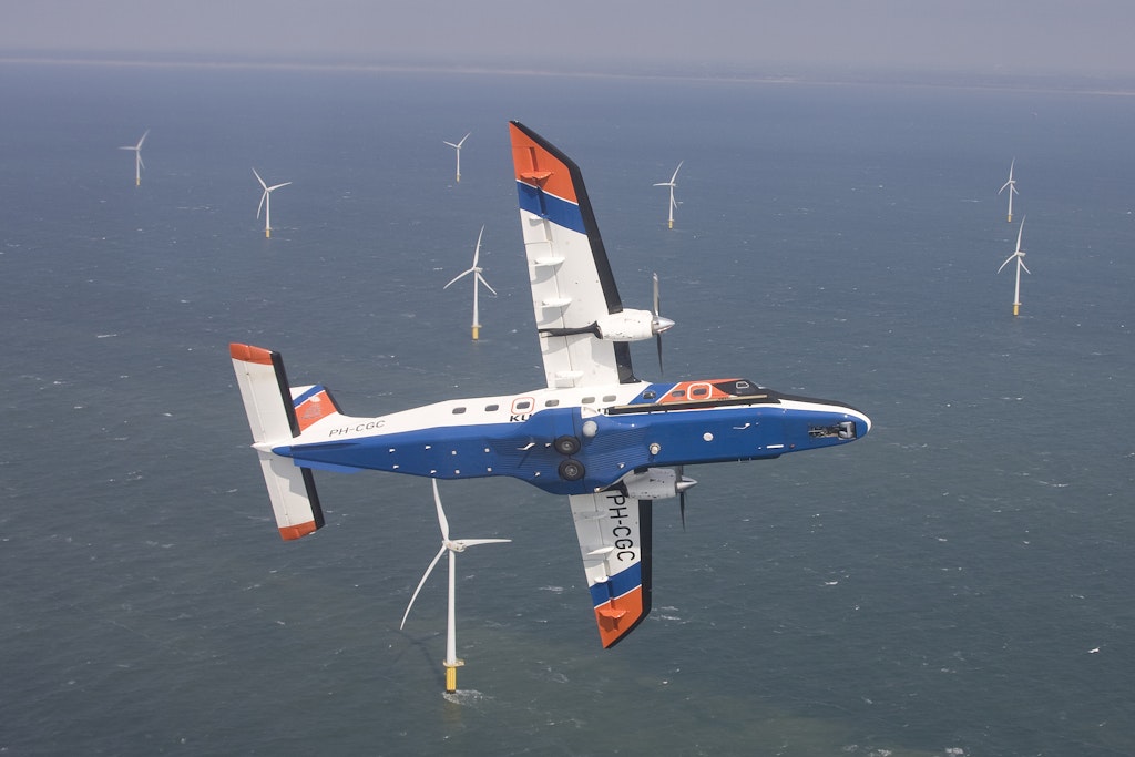 Een vliegtuig van de kustwacht vliegt boven een windpark op zee