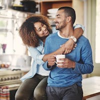 Husband and wife embracing, husband is holding a coffe mug.