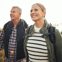Middle aged husband and wife hiking, happy after receiving SLT laser treatments.