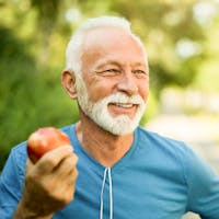 Old man working out and enjoying an apple.