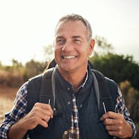 Man smiling while hiking on a trail.