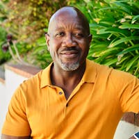 Middle aged man, wearing an orange shirt, smiling at the camera.