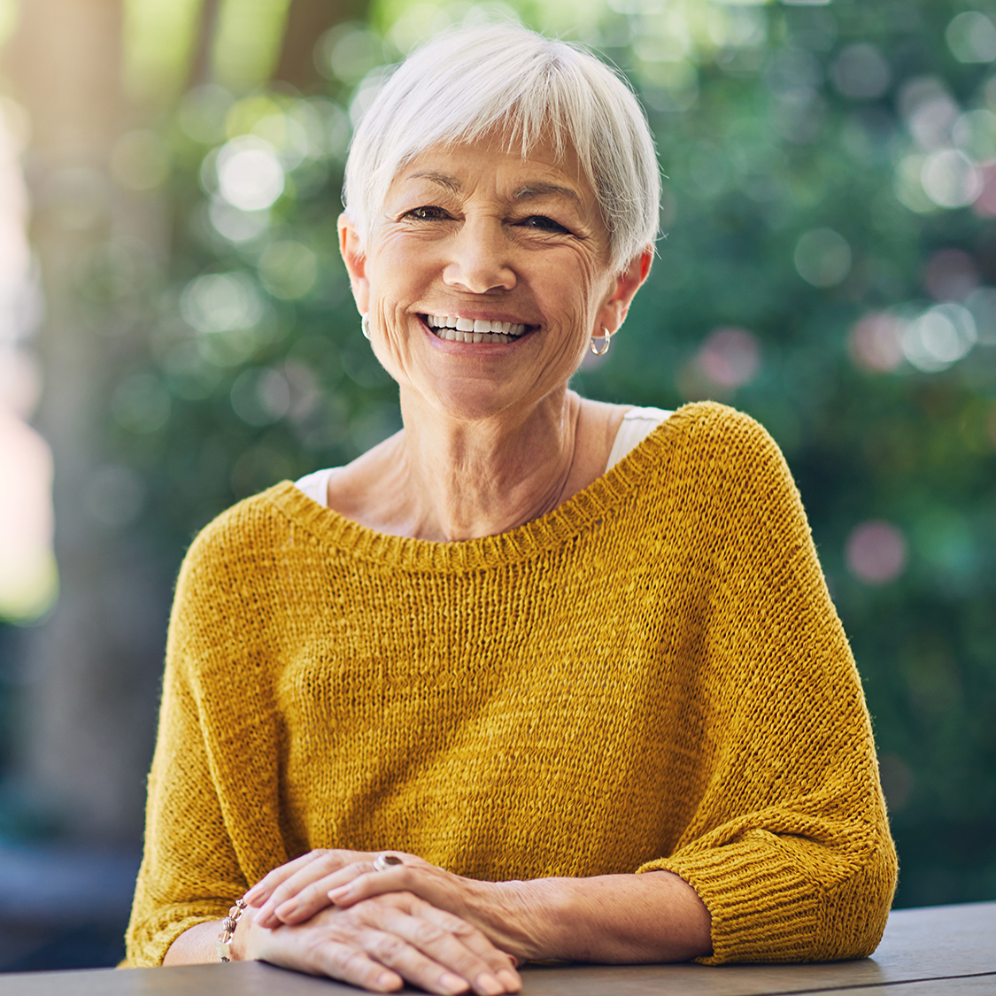 Happy woman after receiving laser cataract surgery, while wearing a yellow sweater. 