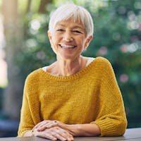 Happy woman after receiving laser cataract surgery, while wearing a yellow sweater.