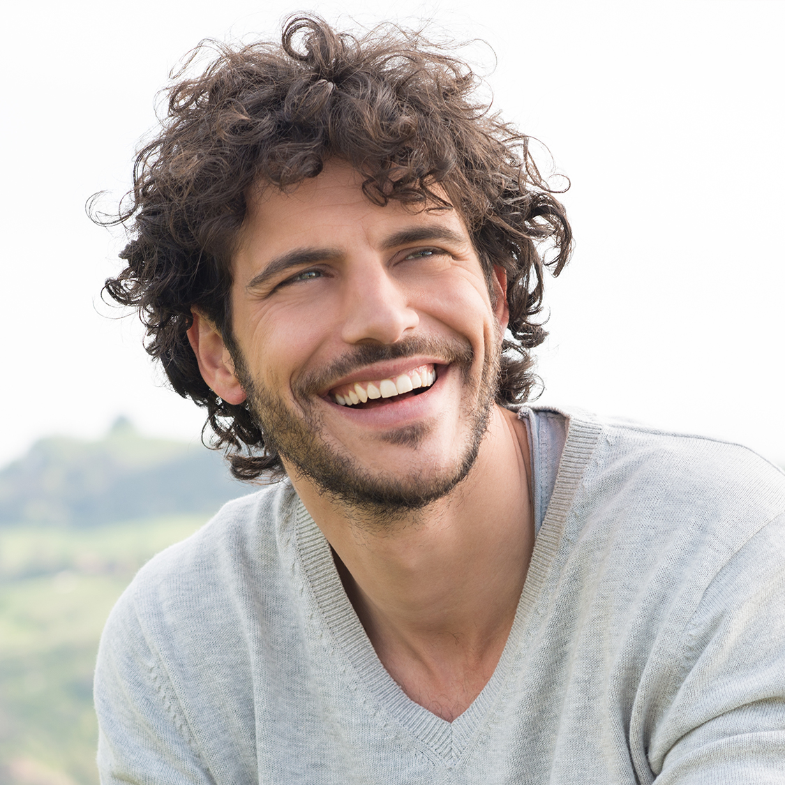 Man smiling, wearing a grey sweater. 