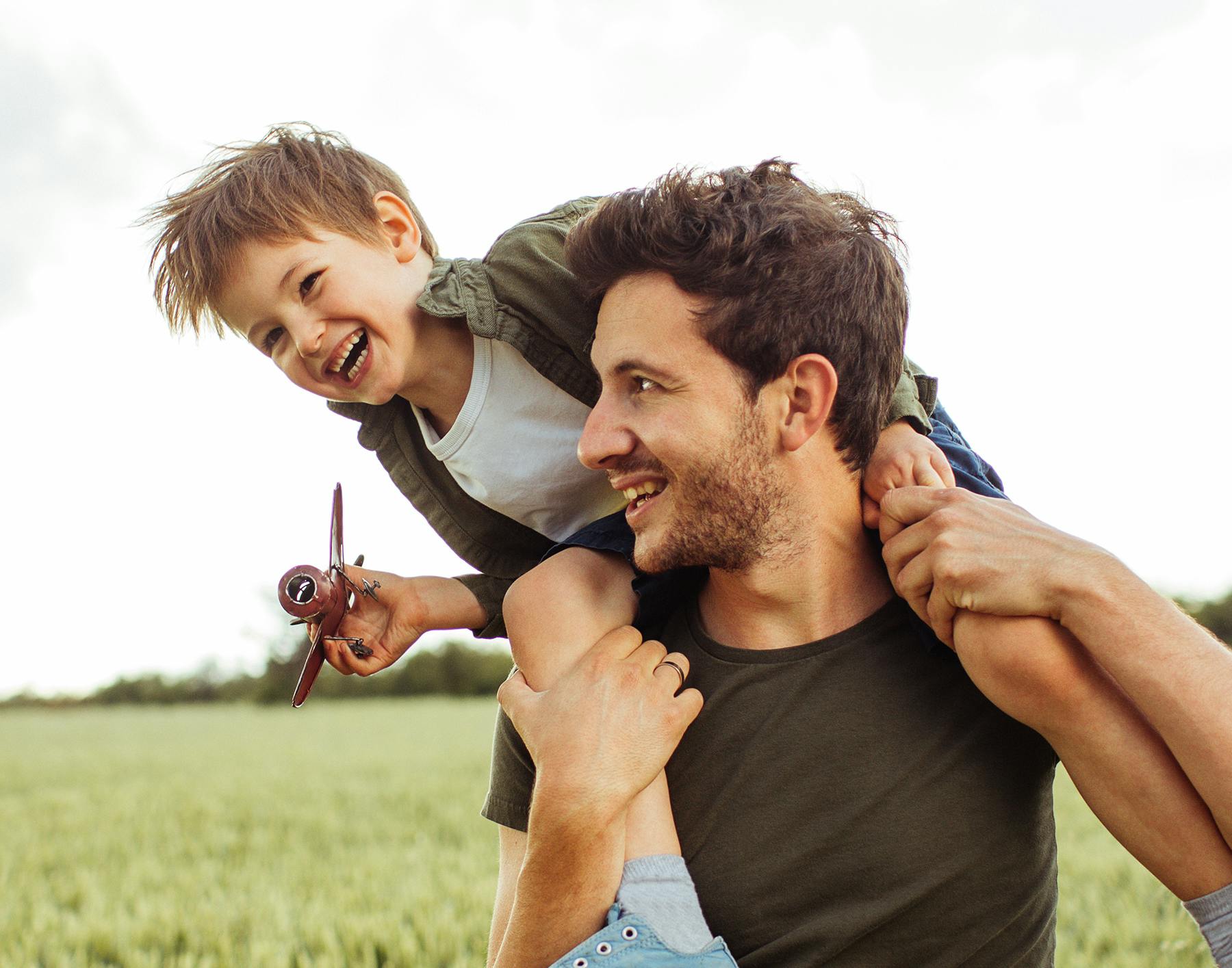 there is a man holding a child on his shoulders in a field