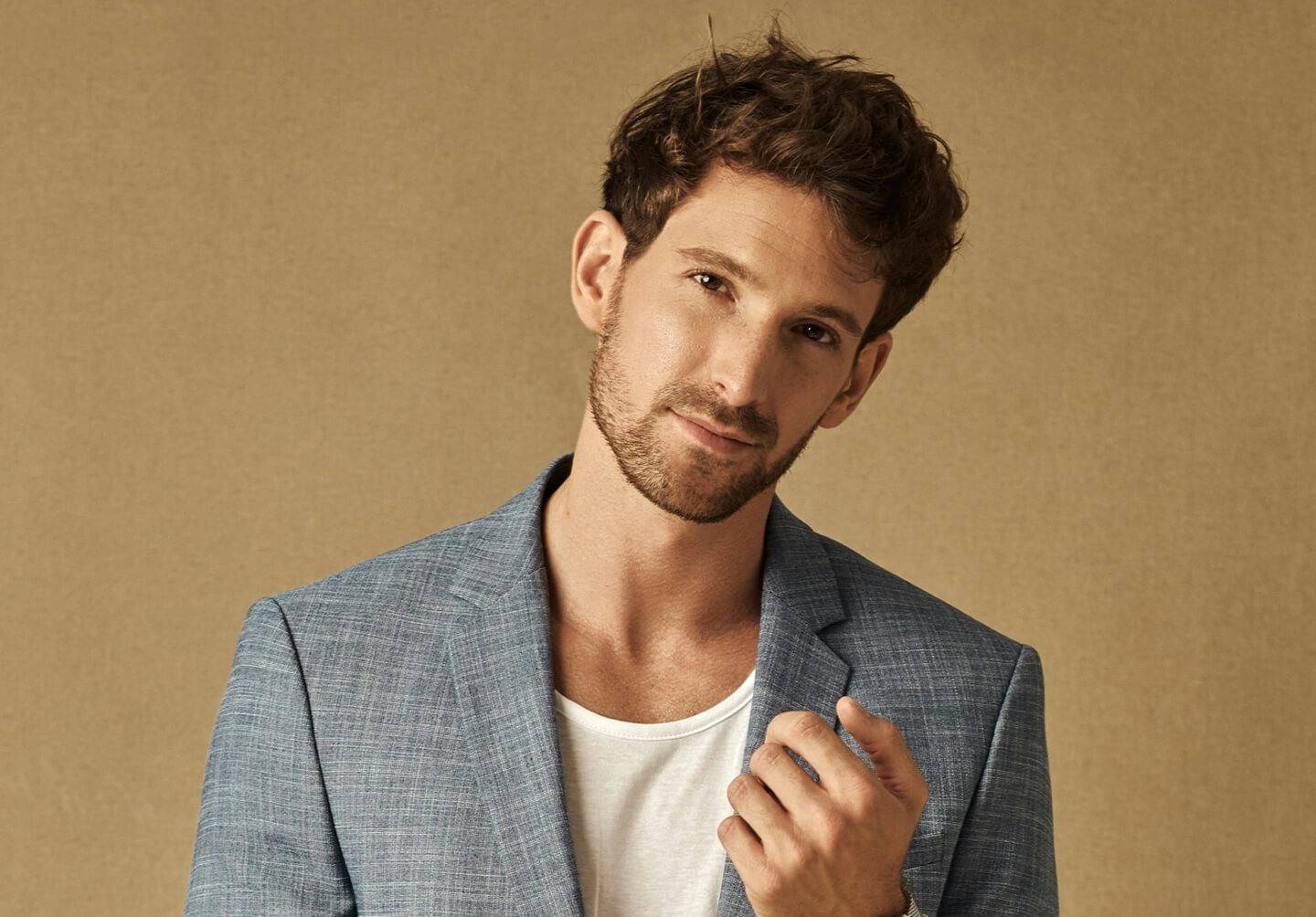 man in a blue suit and white shirt posing for a picture