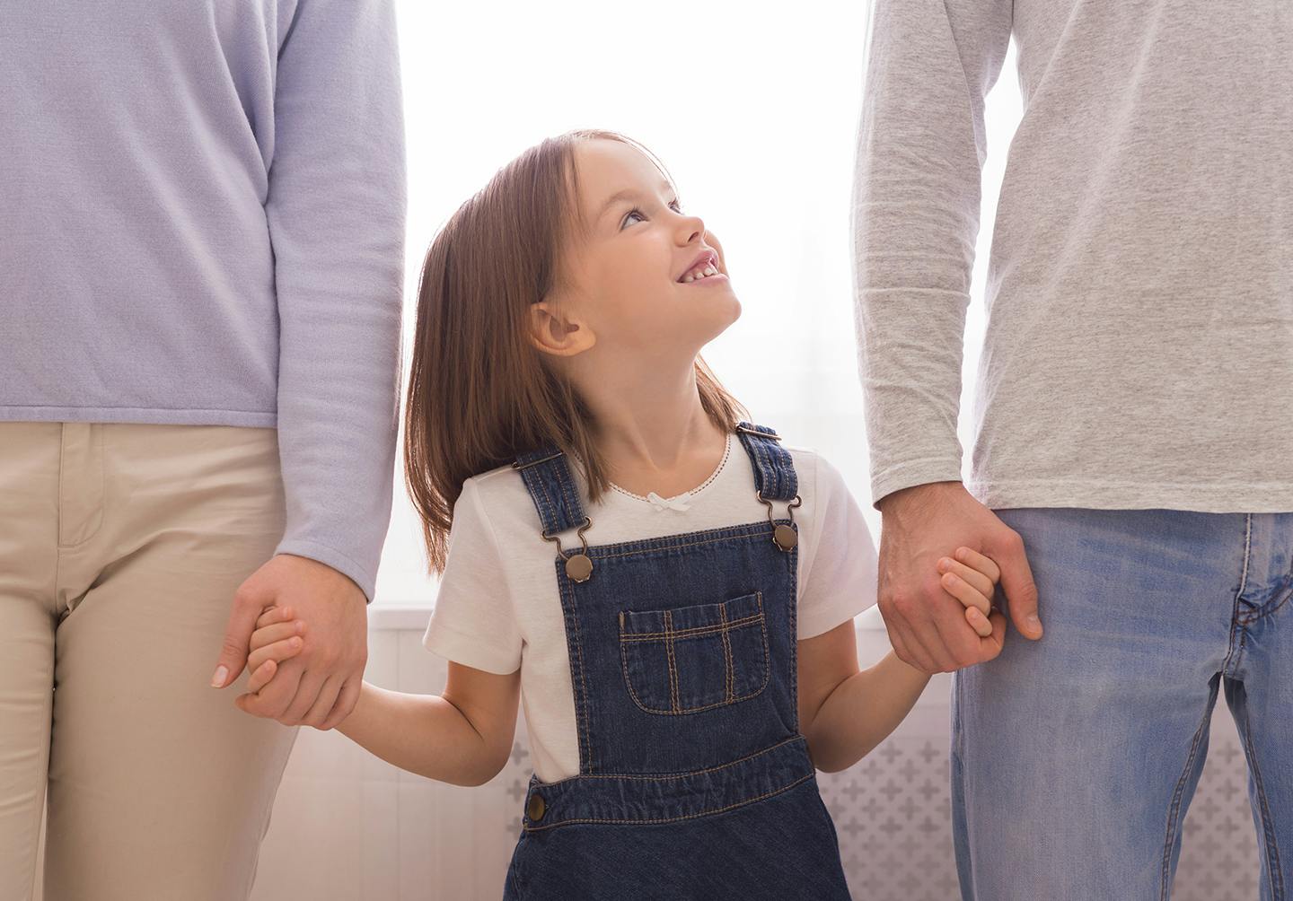 there is a little girl holding hands with her parents