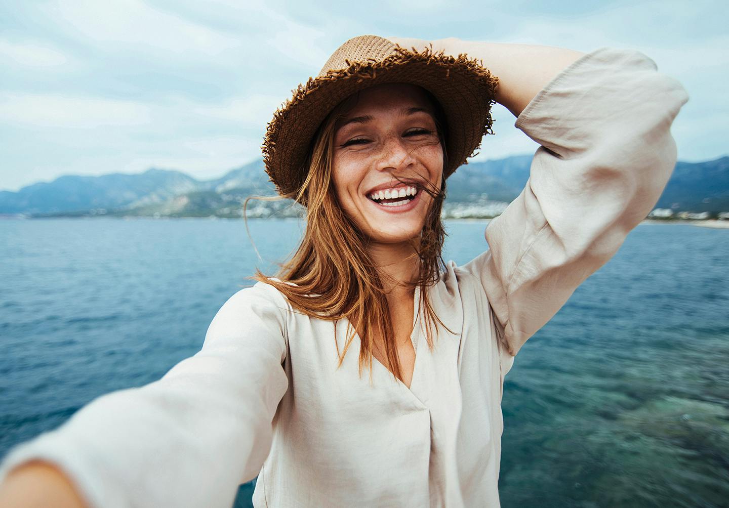 smiling woman in a straw hat taking a selfie on a boat