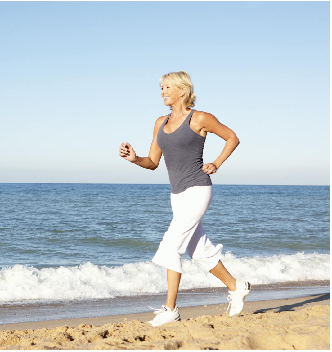 woman running on the beach with a blue sky and ocean in the background