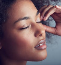 Black woman with hands on face and eyes closed.