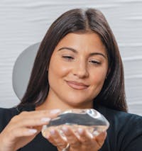 Woman holding a breast implant.