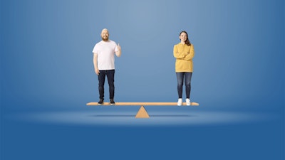 Kaksi henkilöä seisoo tasapainoissa olevan laudan päällä.