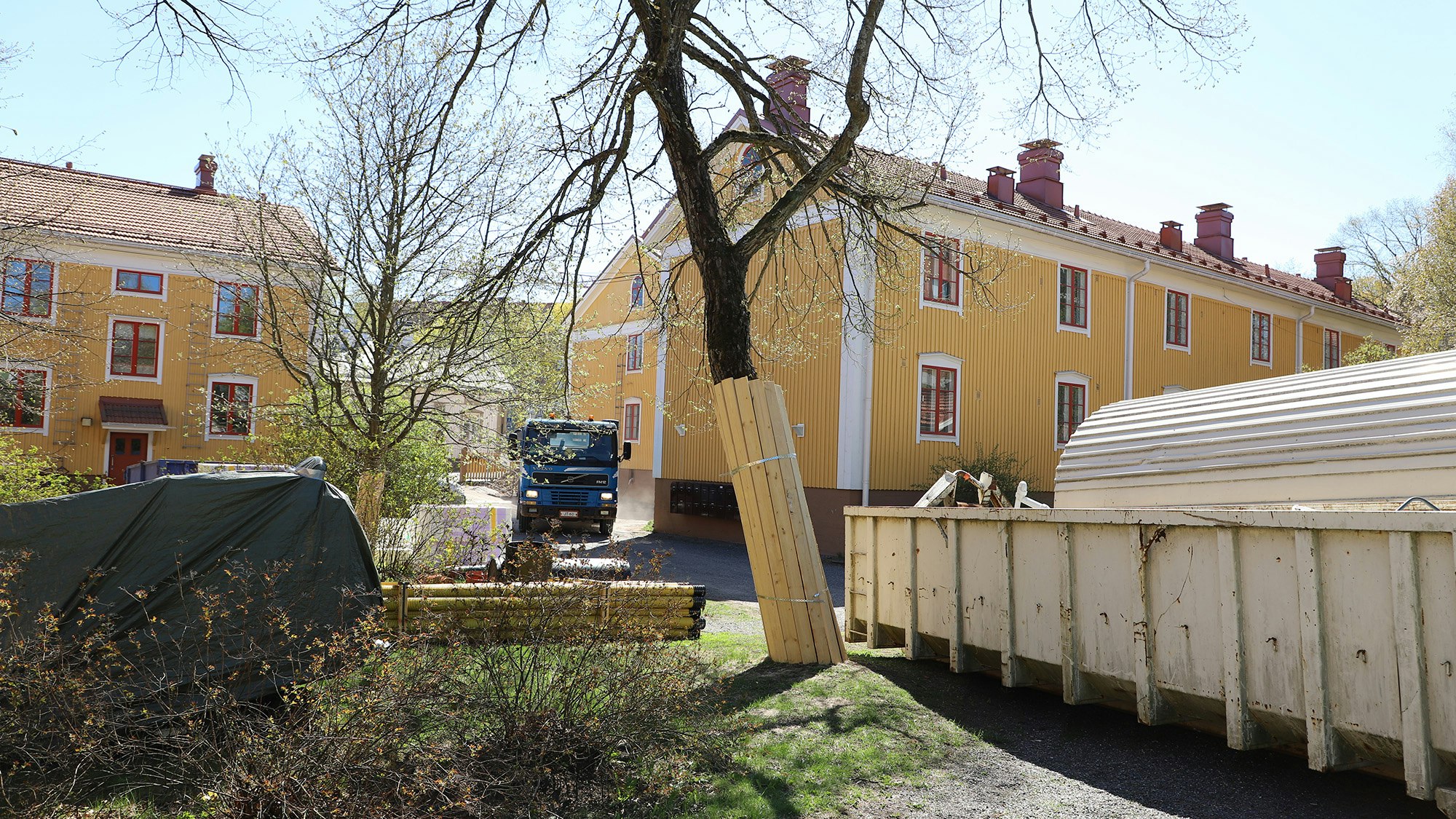 Köydenpunojankatu 5 sisäpihaa remontin aikana. Kuvassa rekka tulossa pihaan, jätelavaa ja muita remonttitarvikkeita näkyvissä.