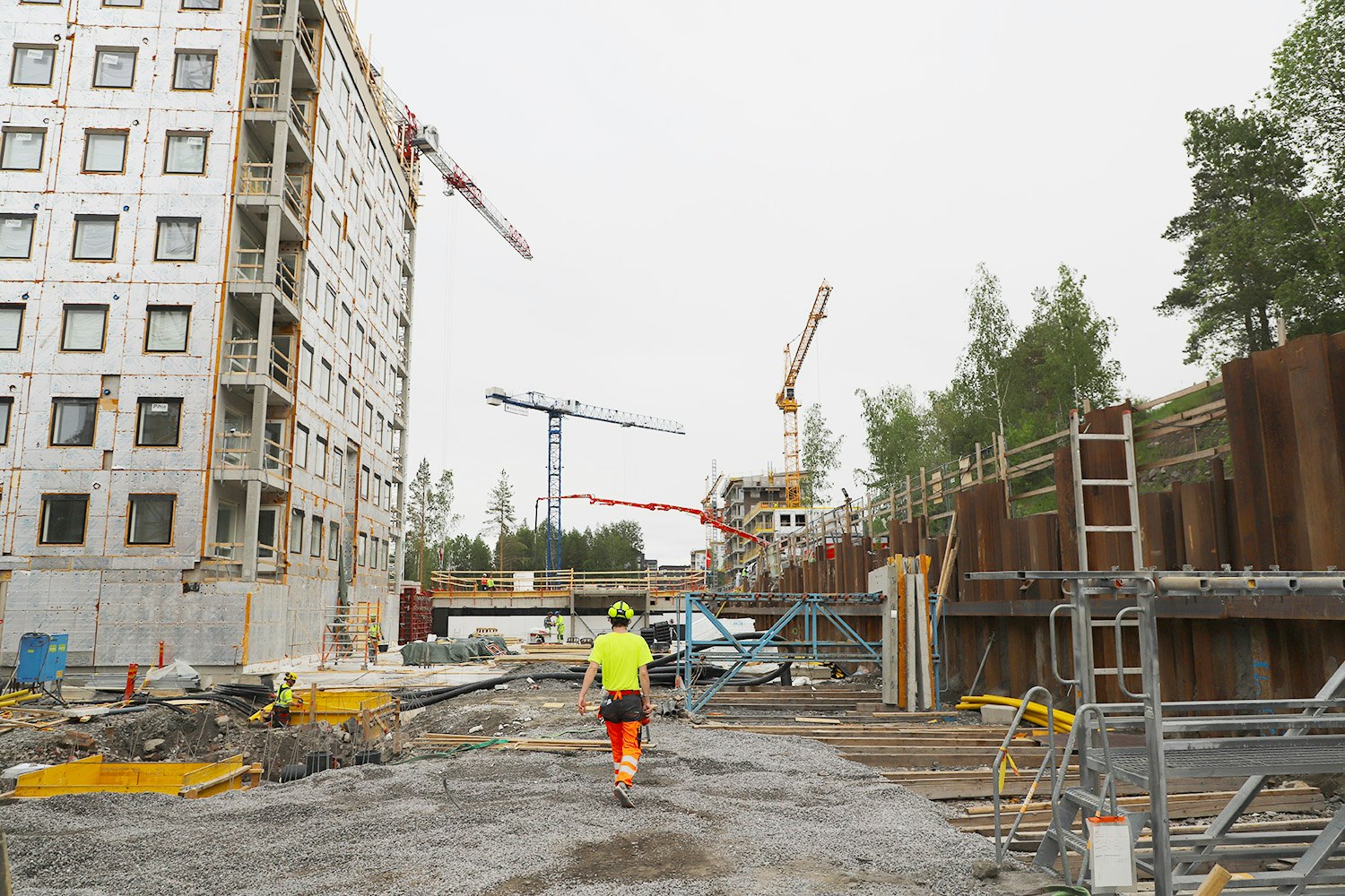 Linkkitorninkatu 7:n rakennustyömaalla. Kuvassa työmies kävelee värikkäissä vaatteissa.