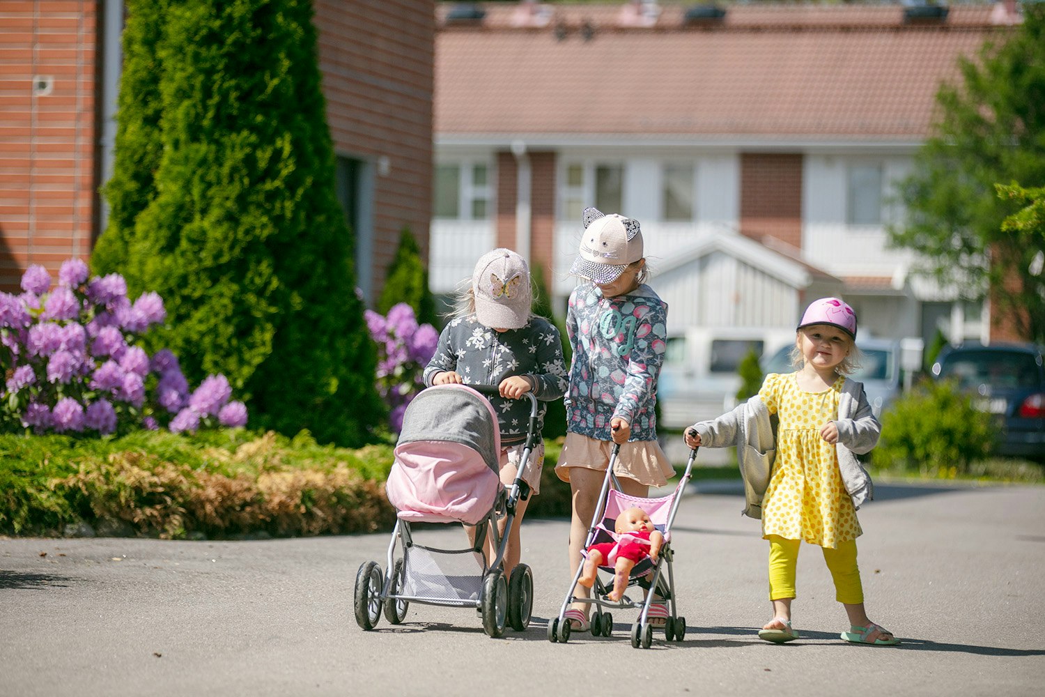 Lapset pihalla työntämässä lelurattaita.