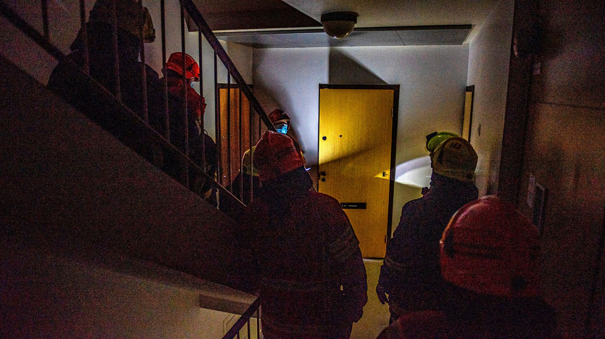 Palomiehet pimeässä rappukäytävässä menossa asuntoon.
