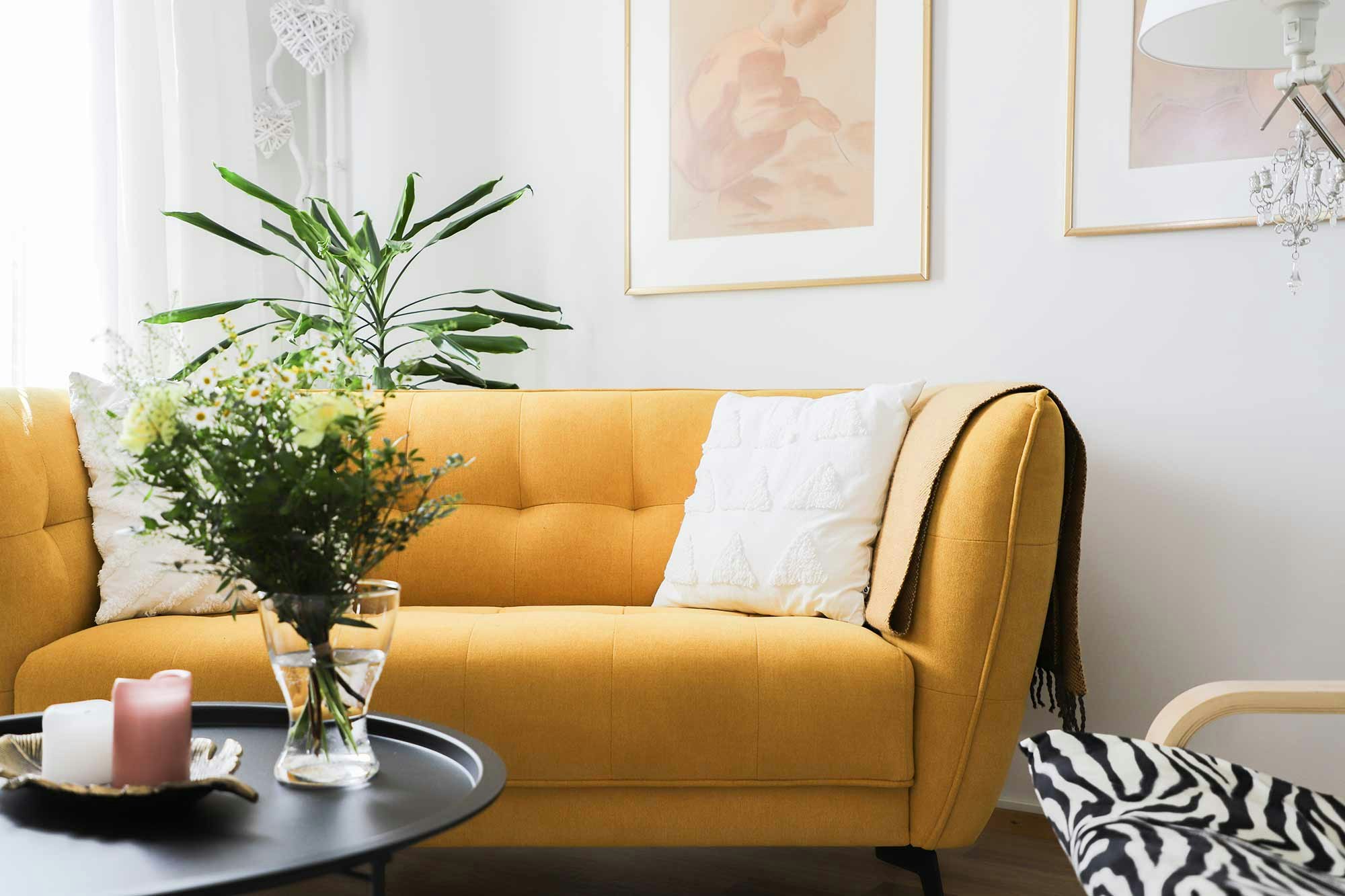 Keltainen sohva, jossa kaksi valkoista tyynyä.