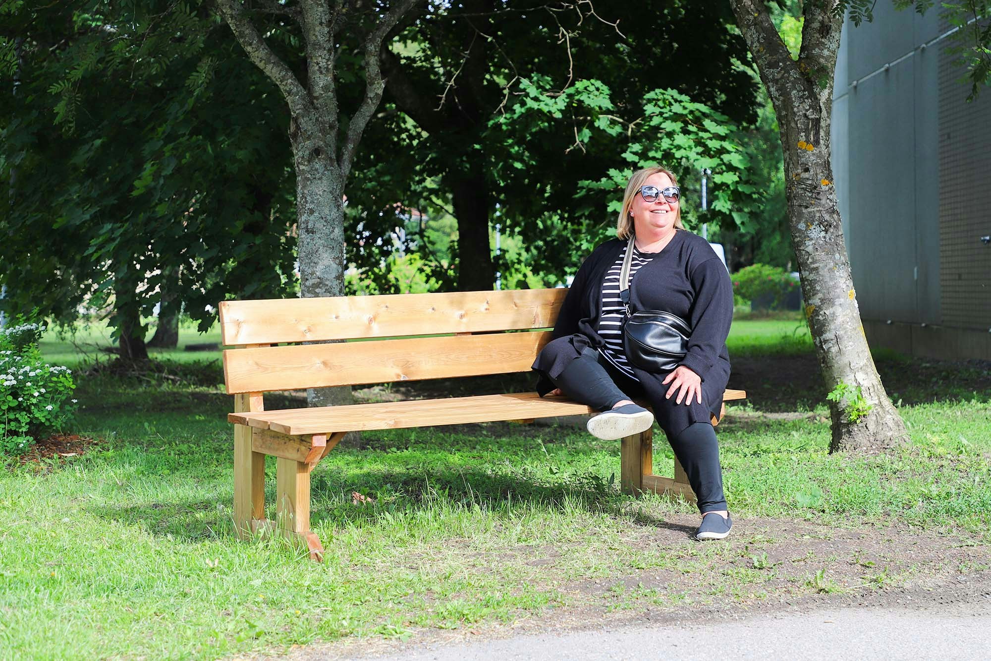 Raivionkujan asukastoimikunnan puheenjohtaja istuu puutarhapenkillä ja hymyilee.