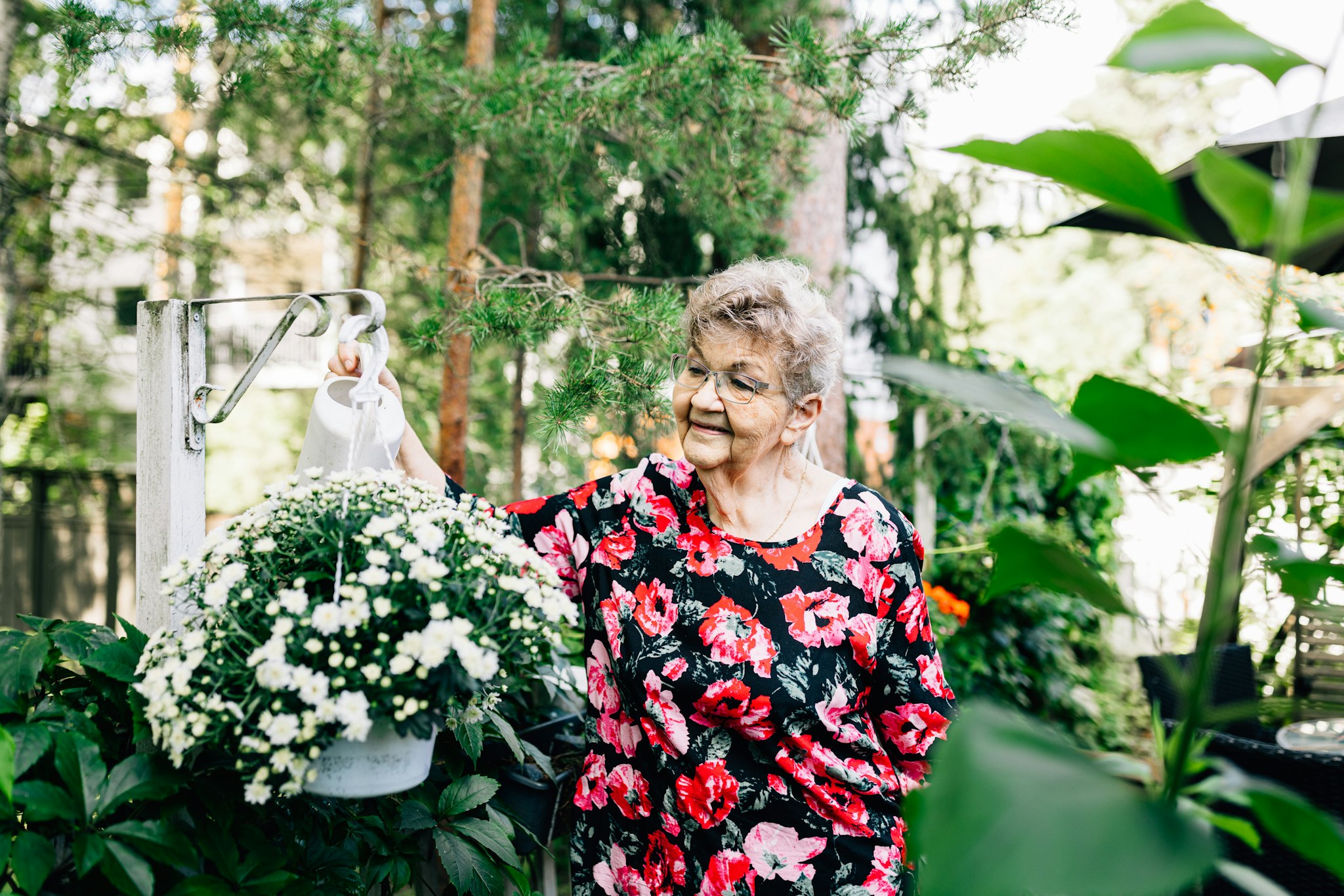Irja Hämäläinen kastelee kukkia puutarhassaan