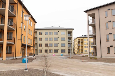 Etualalla vaalea ja oranssi kerrostalo. Takana vaalean vihertävä ja keltainen kerrostalo.