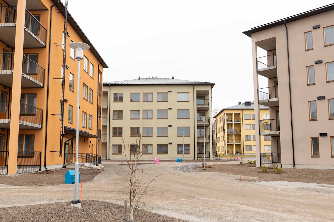 Etualalla vaalea ja oranssi kerrostalo. Takana vaalean vihertävä ja keltainen kerrostalo.