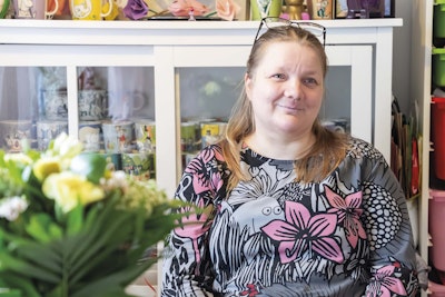 Anu Jaakonsaari istuu keittiön pöydän ääressä ja hymyilee.
