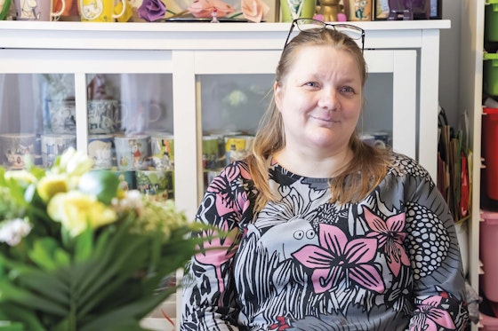 Anu Jaakonsaari istuu keittiön pöydän ääressä ja hymyilee.