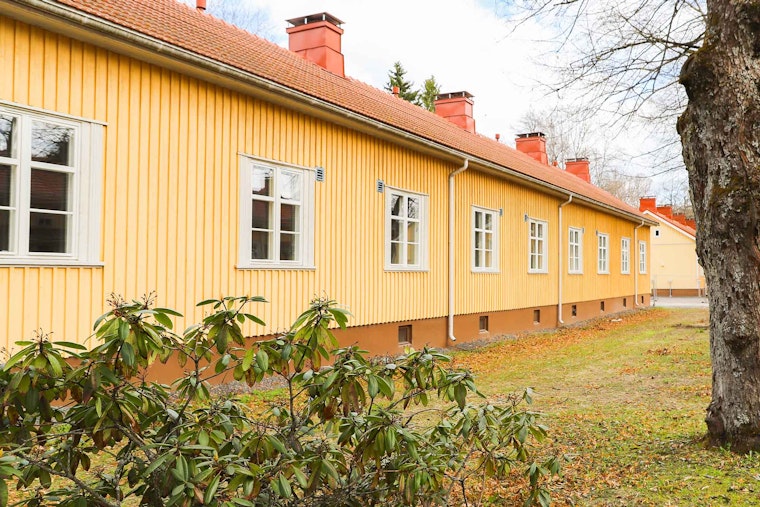 Keltainen puurivitalo, jossa punainen katto.